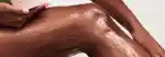 model applying body scrub to their leg